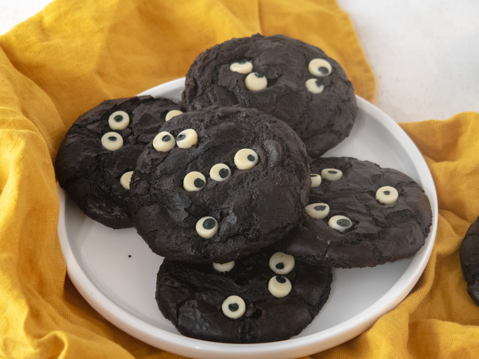 5 cookies on a white plate on top of a orange tablecloth.