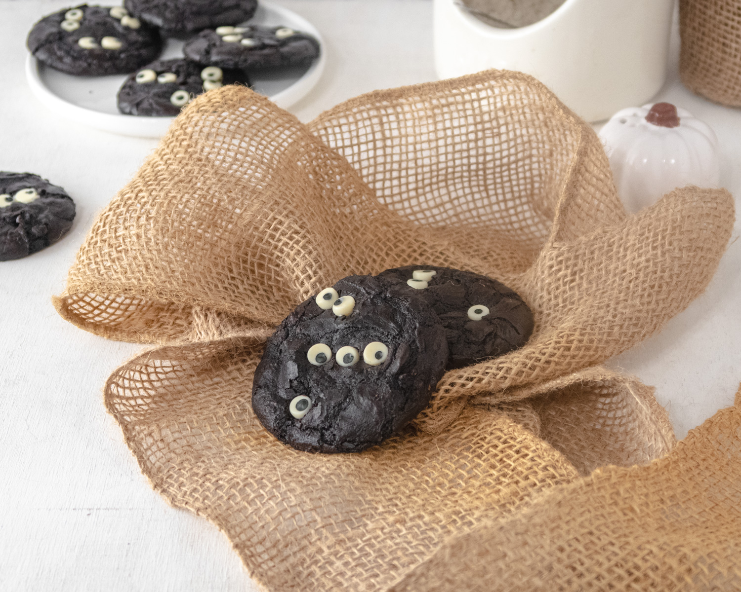 2 spooky brownie cookies in a pile of jute with more cookies in the background.