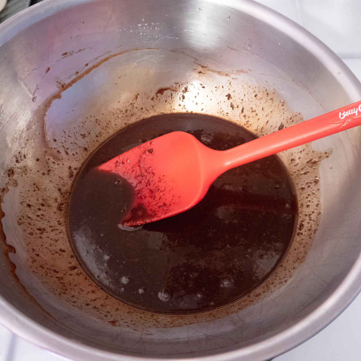 Chocolate slowly melting into a hot sugar syrup and looking split.