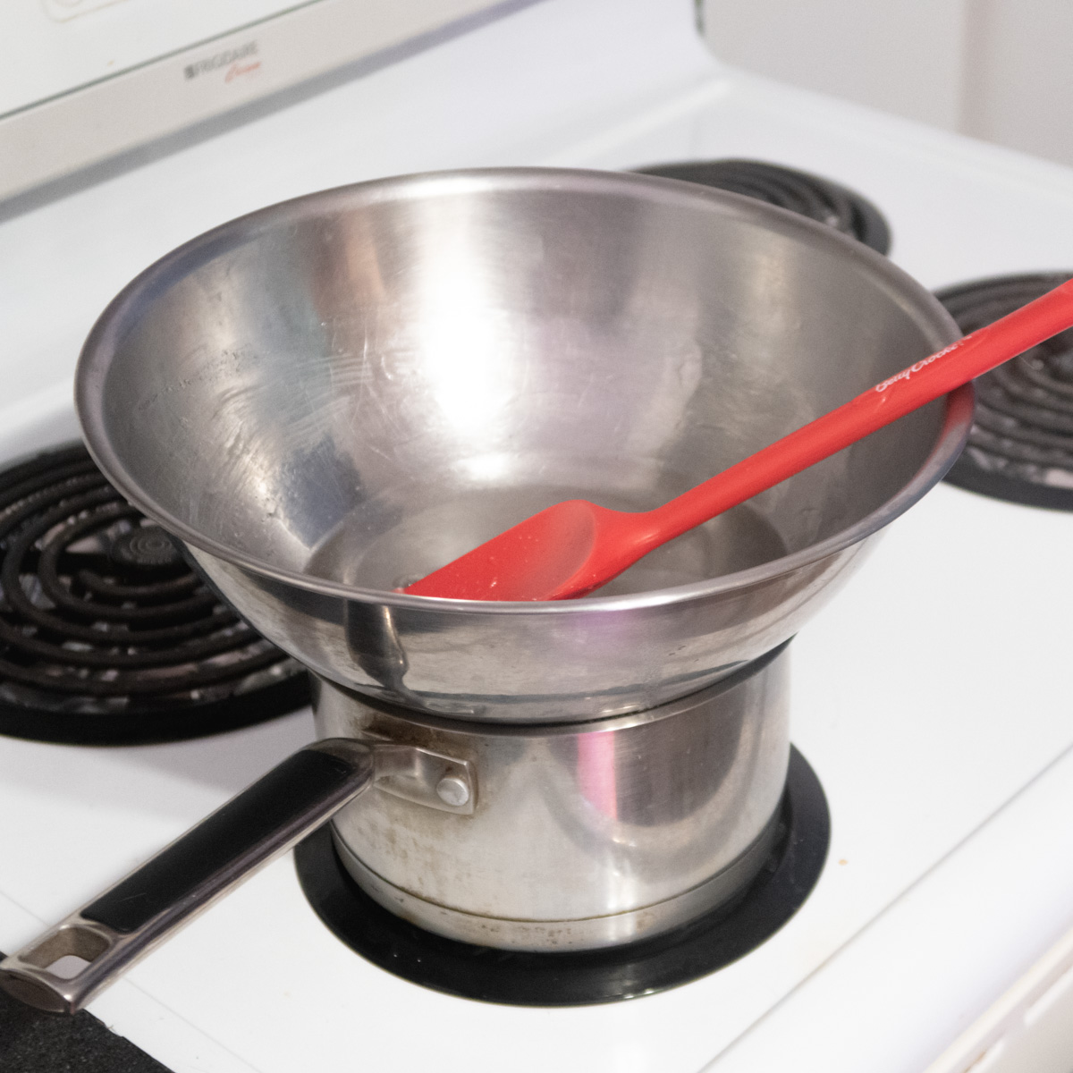A large bowl is placed over a small saucepan to make a double boiler.