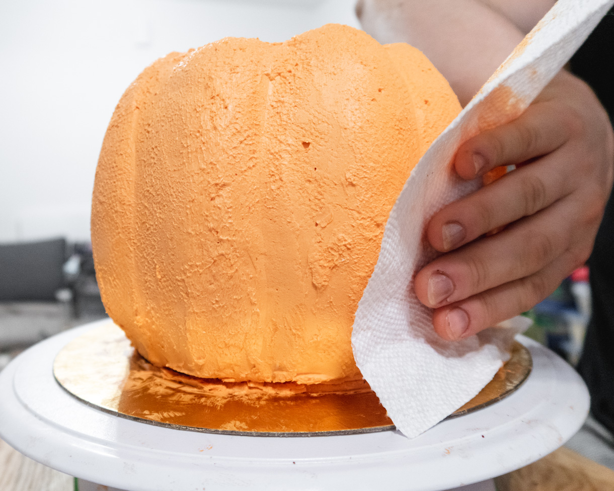 Adding texture to the buttercream surface by pressing a textured paper into the buttercream.