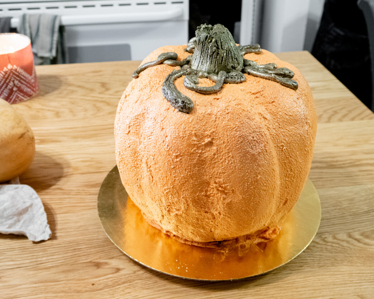 Pumpkin-shaped cake on a wooden table.