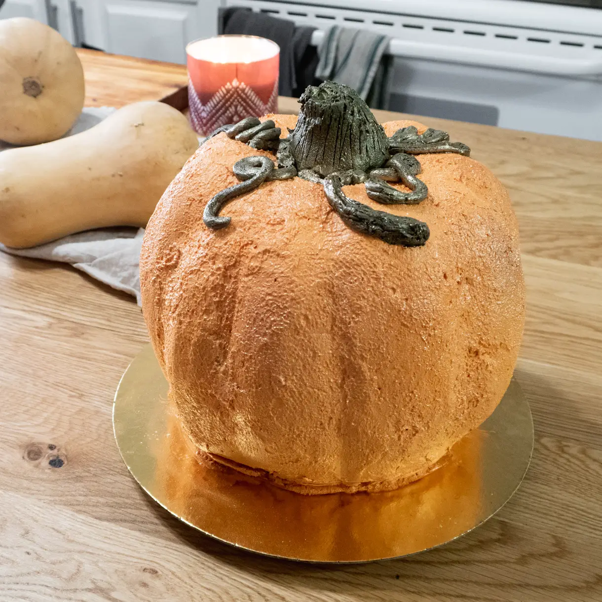 Pumpkin-shaped cake with butternut squash in the background.