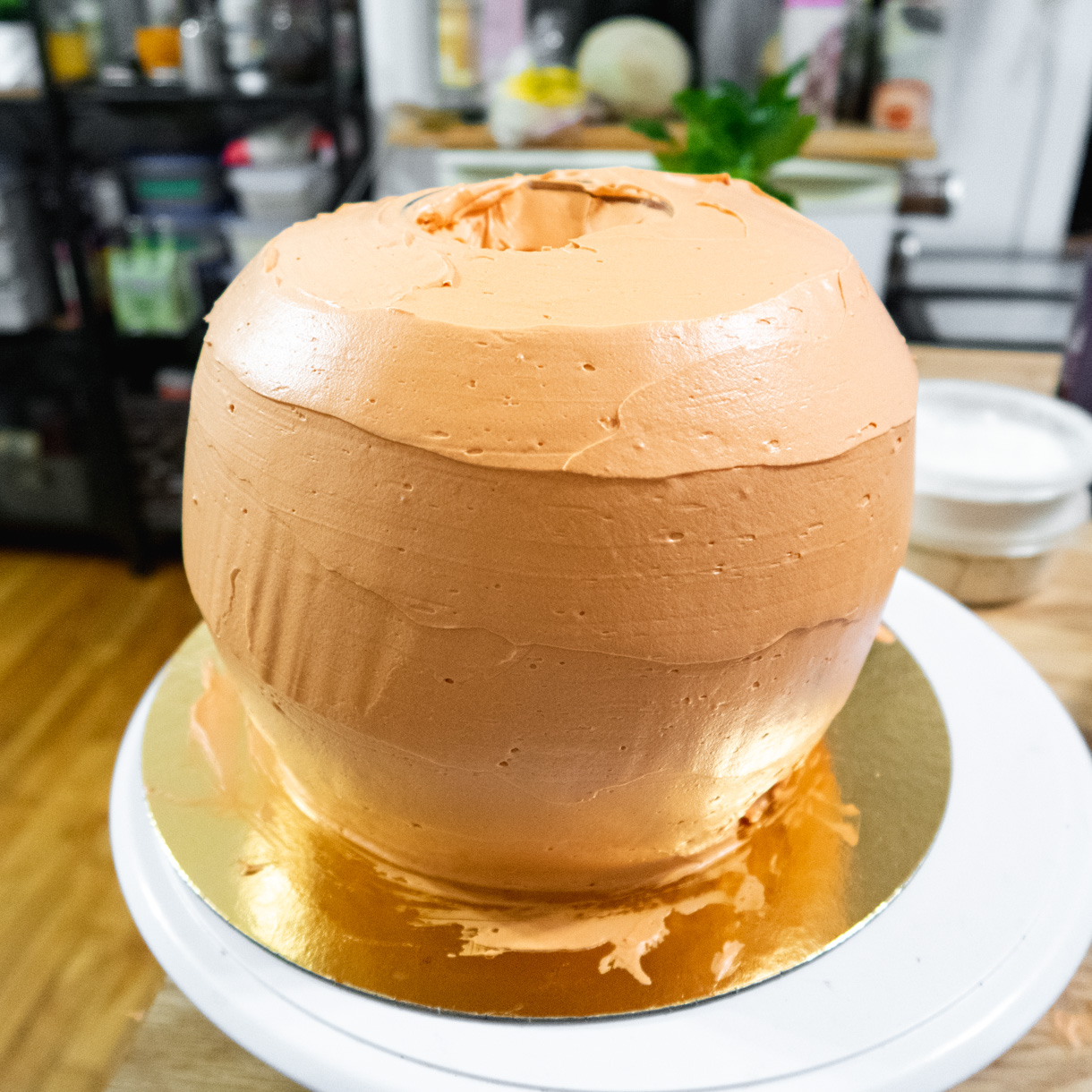 First coat of orange buttercream covering the whole cake.
