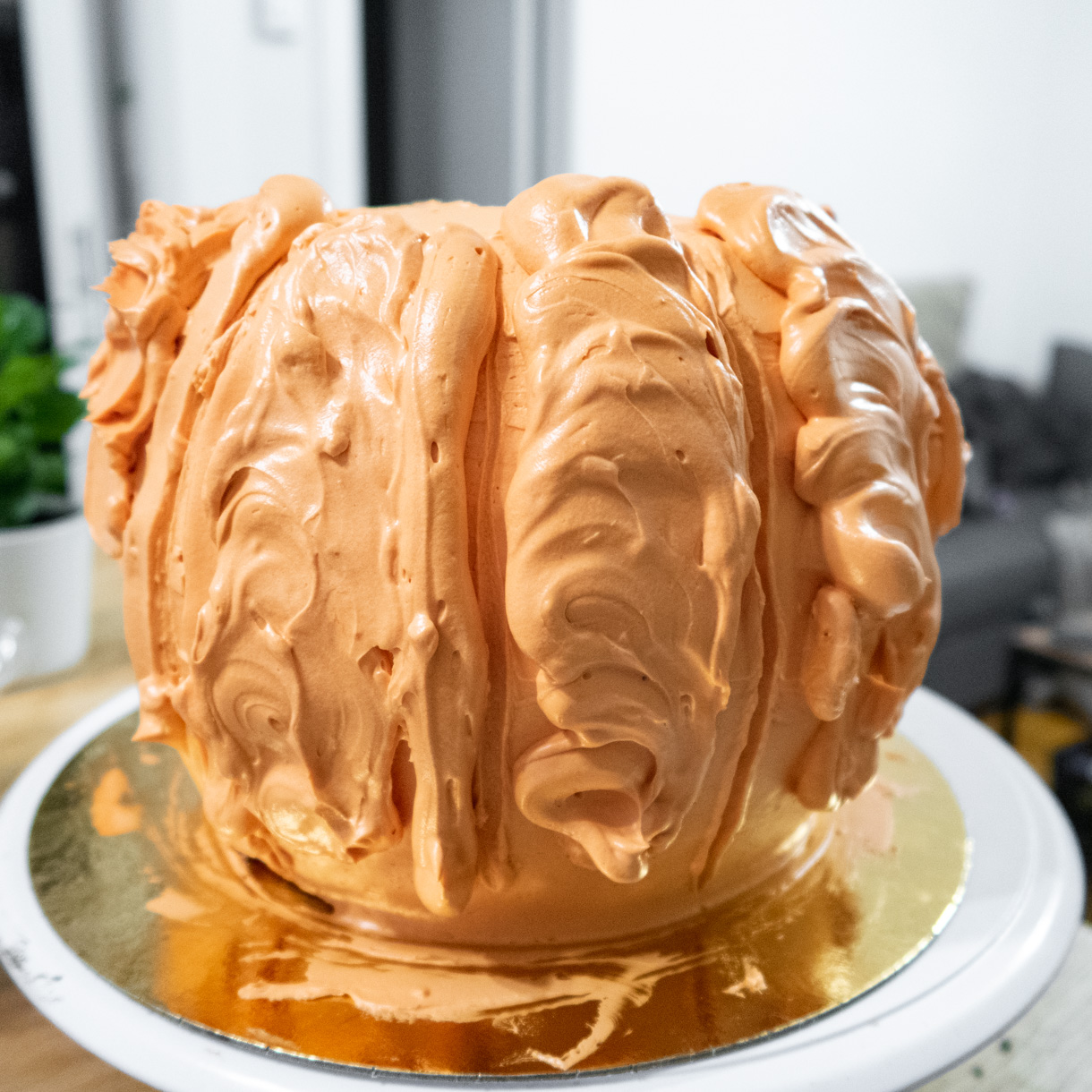 Using piped buttercream to build segments to make the cake look like a pumpkin.