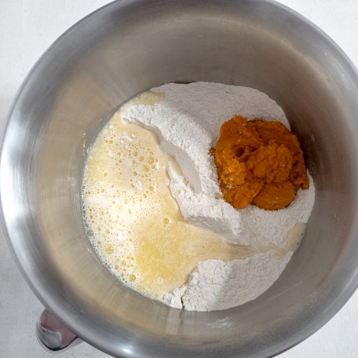 Dry ingredients with the wet ingredients for the doughin the bowl of a stand mixer.