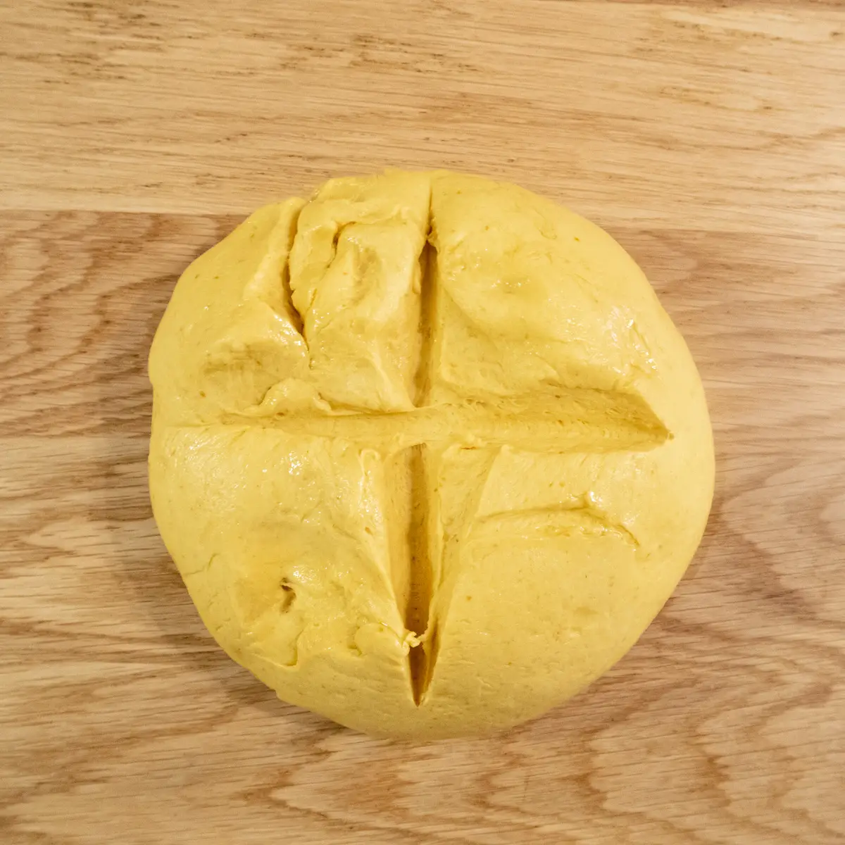 Pumpkin dough ball on a work bench with a cross cut partway through the dough.