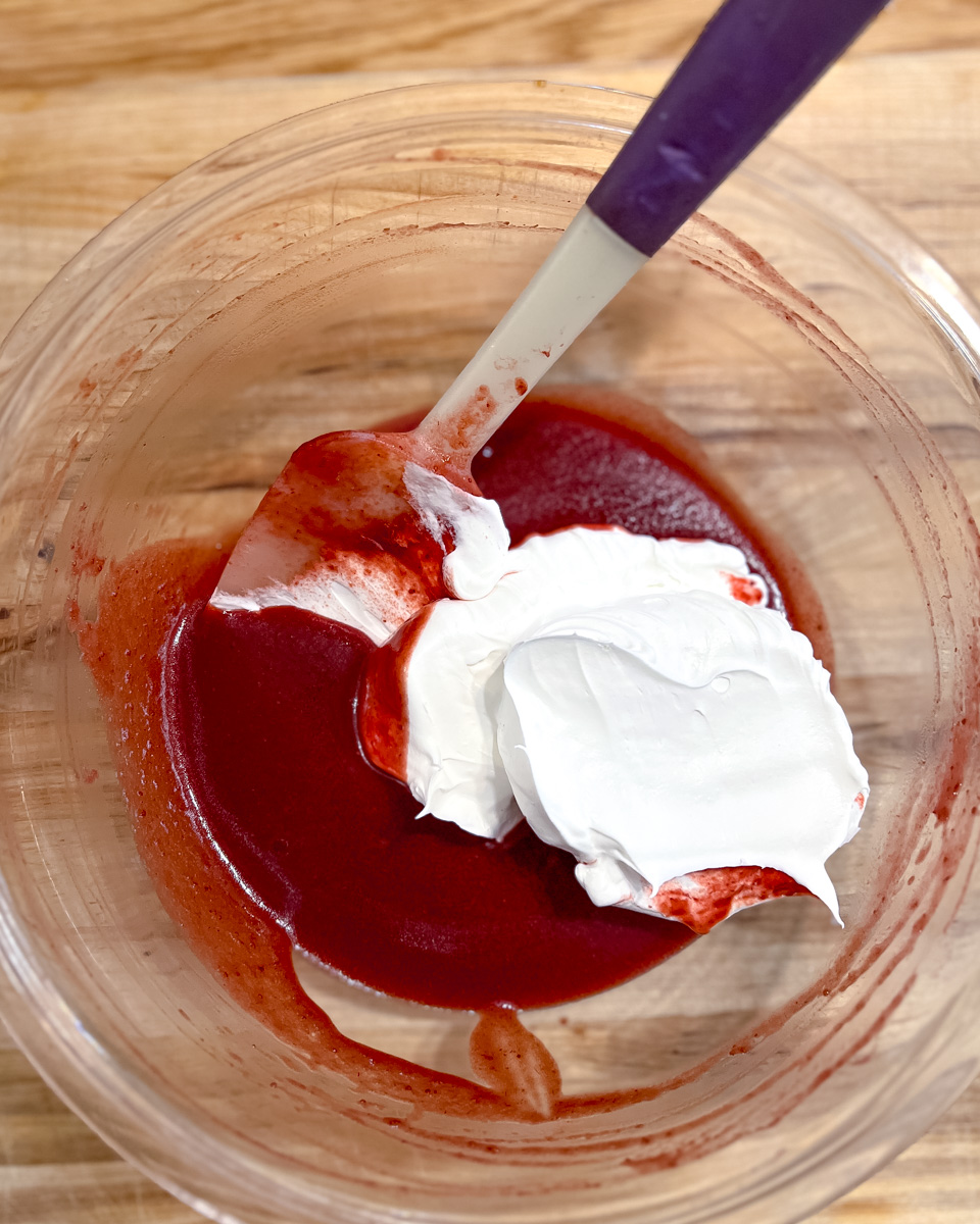 Folding the whipped cream into strawberry ganache.