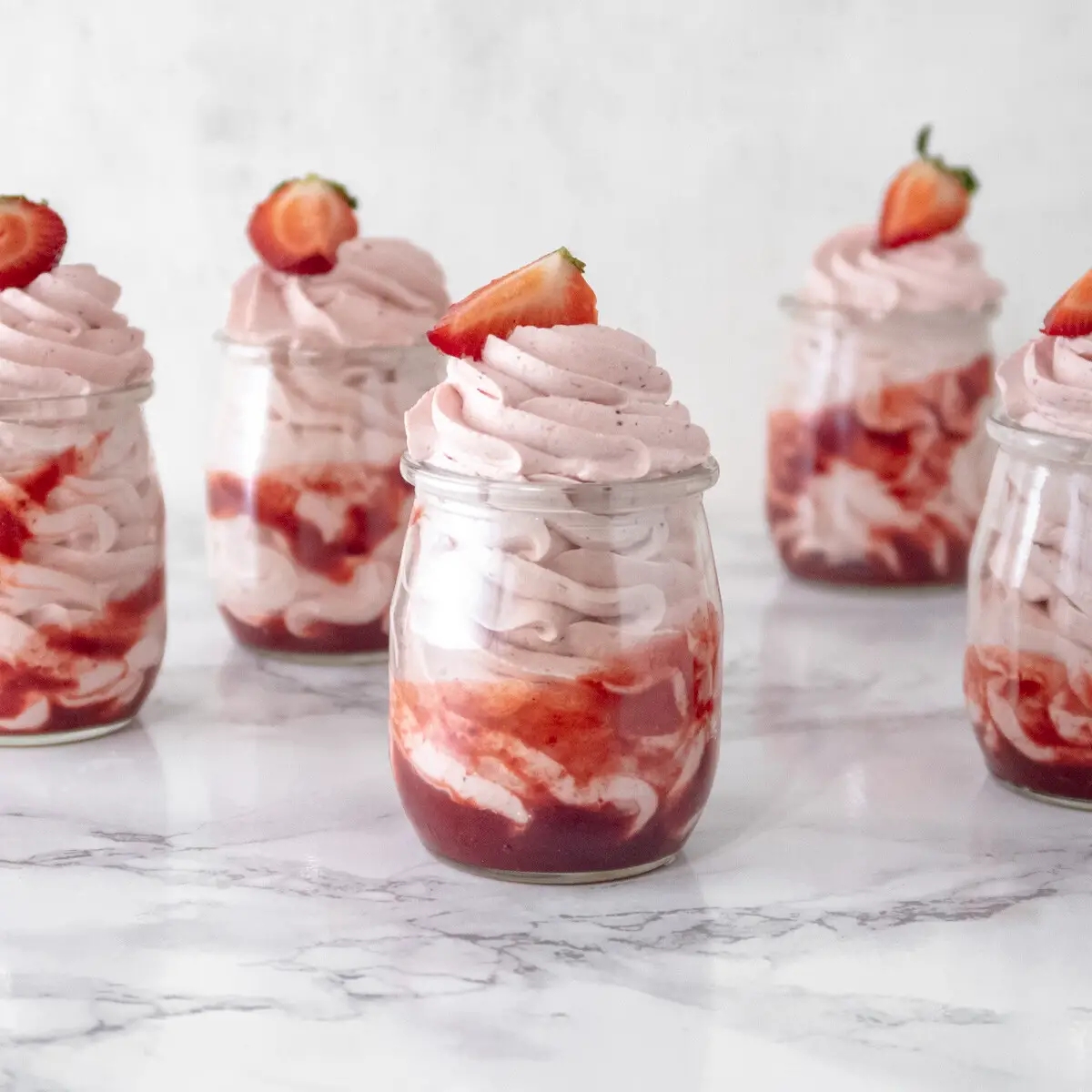 Jars of vegan strawberry mousse in a row.