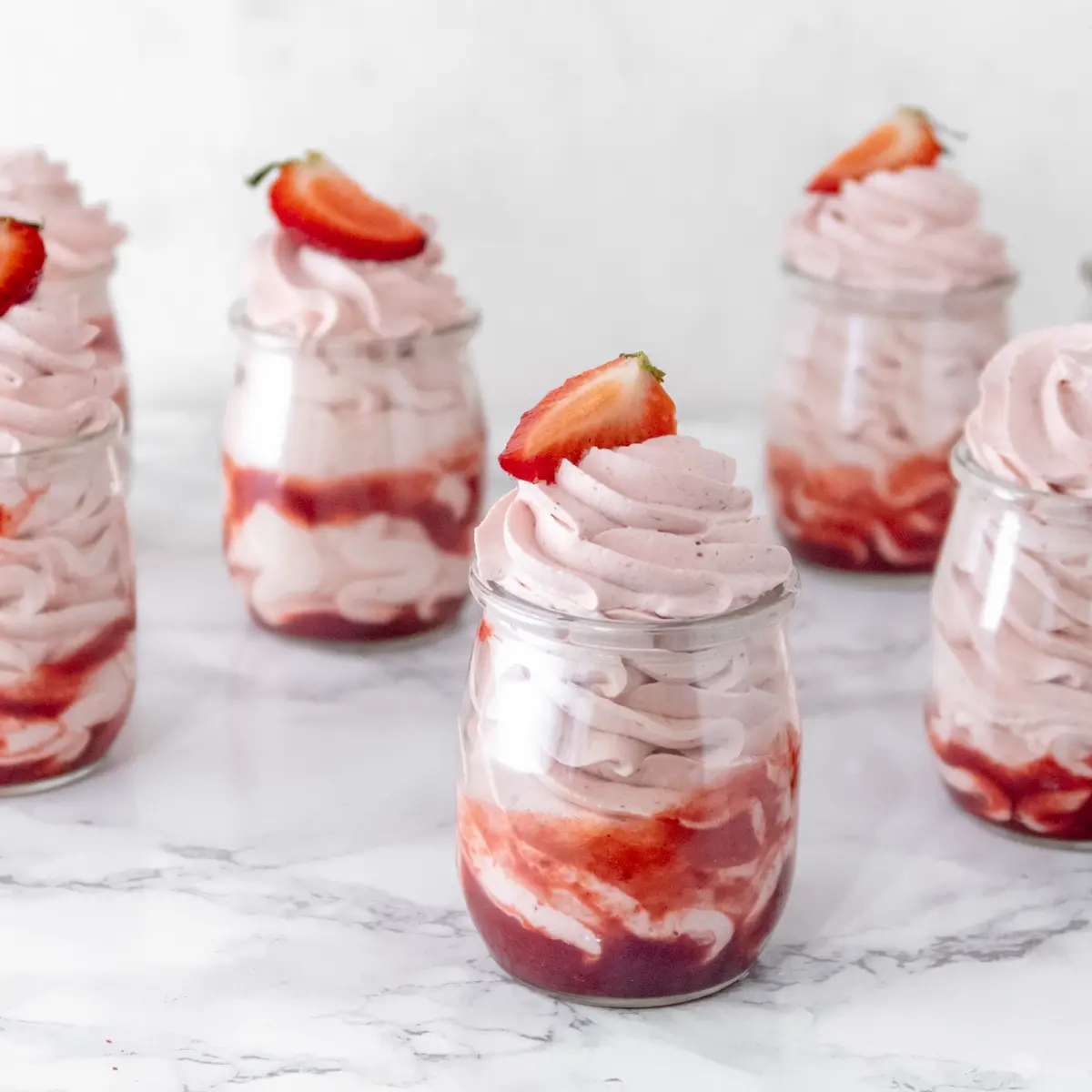 Jars of vegan strawberry mousse in a row.