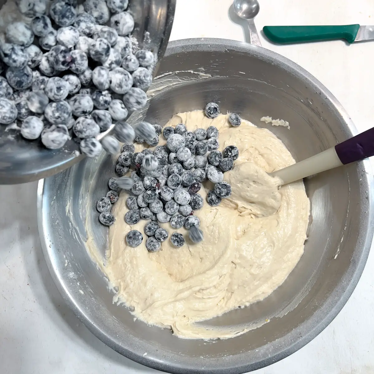 Flour coated blueberries being stirred into the cake batter.